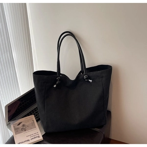 Close-up of black canvas tote bag with unique knotted handle and metallic edge detail