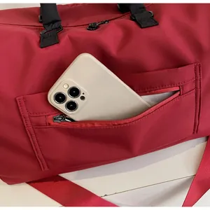 Front zipper pocket of red fitness bag with a smartphone inside for size reference