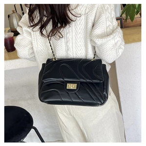 Detail of black quilted leather bag with gold chain strap and square metal turn-lock closure