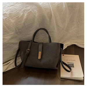 Macro view of dark grey suede texture with a golden oval metal buckle on a tote bag