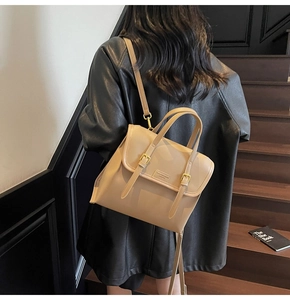 Detail of beige leather backpack with buckle straps and fashion logo on wooden stairs