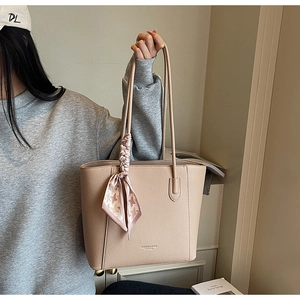 Detail of beige tote bag with litchi leather texture and pink houndstooth silk scarf handle