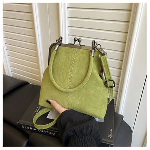 Detail of green suede shell bag featuring vintage metal clasp and top handle straps