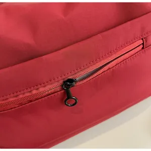 Close-up of smooth zipper with black metal circular puller on red fitness travel bag