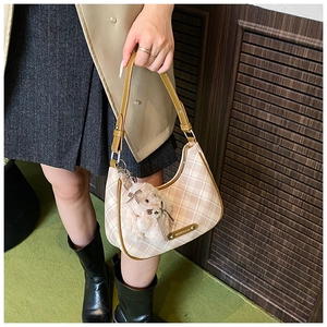Detail of checkered hobo bag with brown leather trim and cute plush rabbit charm