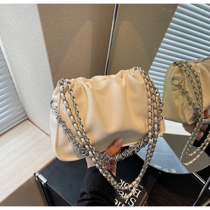 Close-up of beige pleated cloud bag with silver thick chain and soft faux leather texture