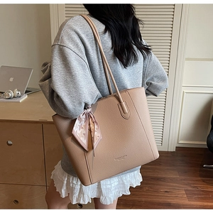 Detail view of a beige large tote bag with lychee texture and decorative silk scarf