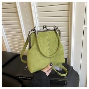 Close-up of avocado green kiss-lock handbag with matte texture and vertical stitching