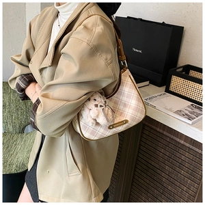 Detail of plaid tote bag with plush rabbit charm and brown leather shoulder strap