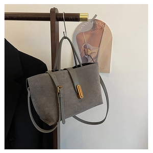 Detail view of grey frosted suede tote bag hanging with metallic gold clasp and strap