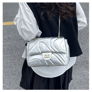 Silver quilted crossbody bag with gold chain strap and twist lock on female model