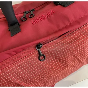 Detail shot of smooth black zippers and red nylon fabric on a large travel bag