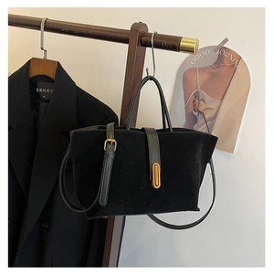 Close-up of black matte suede tote bag with gold oval clasp and smooth leather trim