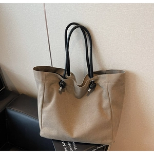 Detail of khaki canvas tote bag with black rope knot handles and modern metal eyelets