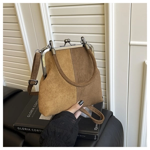Detail of vintage brown suede shell bag with silver metal clip frame and top handle