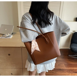 Brown leather tote bag with houndstooth silk scarf detail shown on a model's shoulder