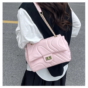 Detailed back-side view of a pink quilted crossbody bag with a gold chain strap on a model