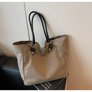 Detailed close-up of dark khaki tote bag showing canvas texture and knotted black handles