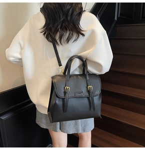 Detail of a vintage black leather backpack with gold buckles and fashion logo embossing