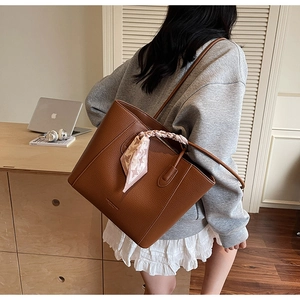 Close-up of brown pebbled leather tote bag with stylish pink checkered scarf on handle