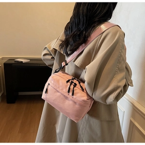 Detail of pink nylon crossbody bag with adjustable strap and multiple zipper pockets