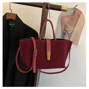 Detail view of burgundy faux suede tote bag with gold decorative buckle and strap
