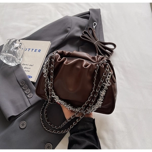 Detail of dark brown pleated dumpling bag with chunky metal chain and leather strap