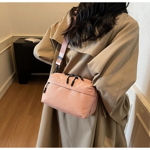 Pink nylon crossbody bag shown worn by model with adjustable shoulder strap