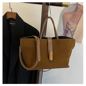 Detail of vintage brown suede tote bag with golden buckle and adjustable shoulder strap