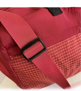 Detail of adjustable shoulder strap and reinforced nylon fabric on burgundy sports bag