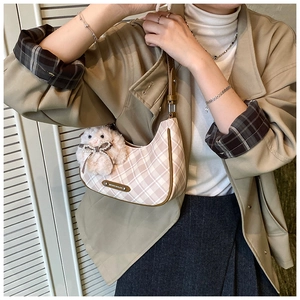 Model wearing a large pink plaid tote bag with a white plush lamb charm on a shoulder