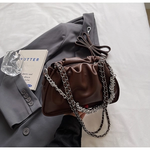 Detailed view of dark brown pleated bucket bag with silver chain strap and leather strap