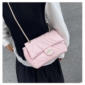 Detail of pink quilted shoulder bag featuring gold chain strap and wavy stitching texture