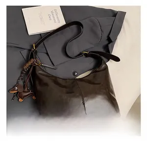 Detail of dark brown leather hobo bag with vintage texture and dachshund charm