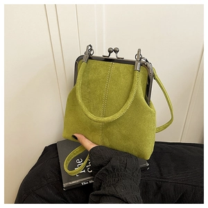 Close-up of green suede shell handbag with vintage metal frame clasp and white stitching