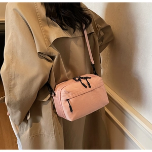 Detailed view of a pink nylon crossbody camera bag shown from a side-back model perspective