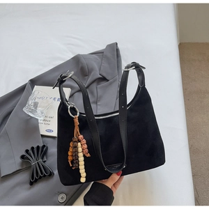 Vue détaillée du sac en daim noir mat avec pendentif décoratif en perles de bois