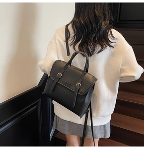 Detail of vintage black matte leather backpack with decorative buckle straps on stairs