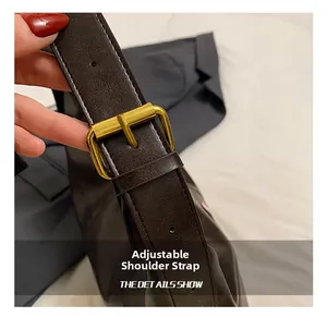 Detail of adjustable leather shoulder strap with golden metal buckle for bucket bag