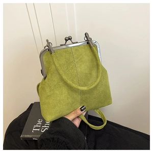 Detail of vintage avocado green suede handbag featuring a classic metal kiss-lock closure