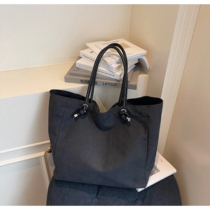 Detail of black canvas tote bag showing silver eyelets and knotted rope handle design