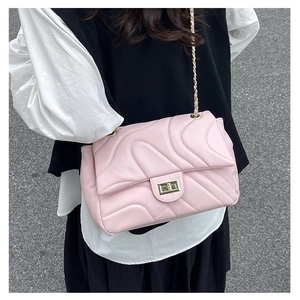 Detail of pink quilted crossbody bag with gold lock and chain strap on a model