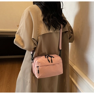 Rear view of pink canvas crossbody bag worn with a beige trench coat for leisure style