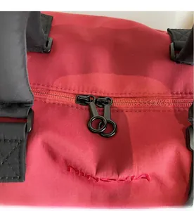 Close-up of dual circular zippers and embroidered logo on red sports gym duffel bag