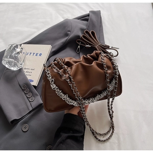 Detail of dark brown pleated cloud bag with silver chain strap on grey blazer