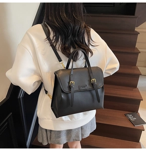 Close-up of black retro leather backpack with golden metal buckle and fashion logo plate