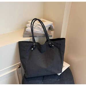 Close-up of black canvas tote bag showing the textured fabric and silver metal eyelet details