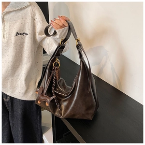 Detail of deep brown hobo bag with gold metal buckle and cute dog leather charm