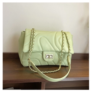 Close-up of light green quilted shoulder bag with wave stitching and gold chain strap