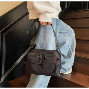 Detailed view of black nylon crossbody bag with adjustable strap on a street model